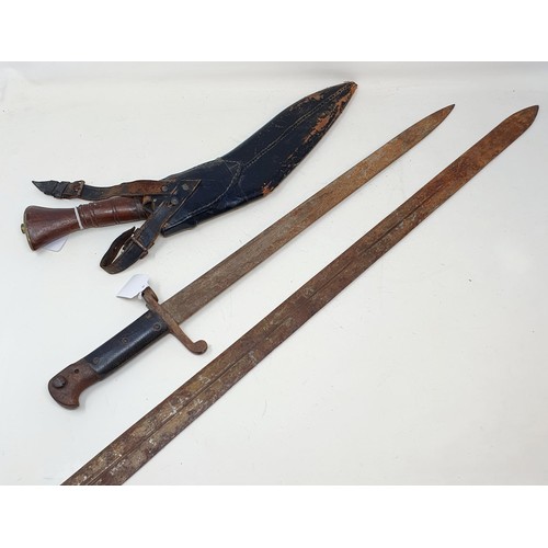 186 - An early 20th century bayonet, 59 cm long, a sword, 103 cm long, and a Kukri and scabbard, 44 cm (3)