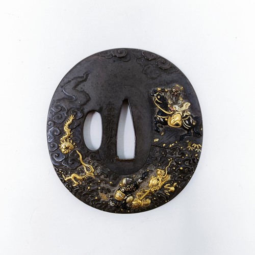 167 - A Japanese bronze tsuba, inlaid with gold, decorated a figure on horseback, and a dragon to one side... 