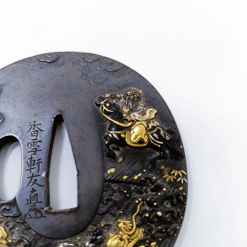 167 - A Japanese bronze tsuba, inlaid with gold, decorated a figure on horseback, and a dragon to one side... 