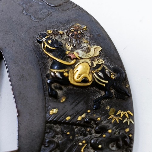 167 - A Japanese bronze tsuba, inlaid with gold, decorated a figure on horseback, and a dragon to one side... 