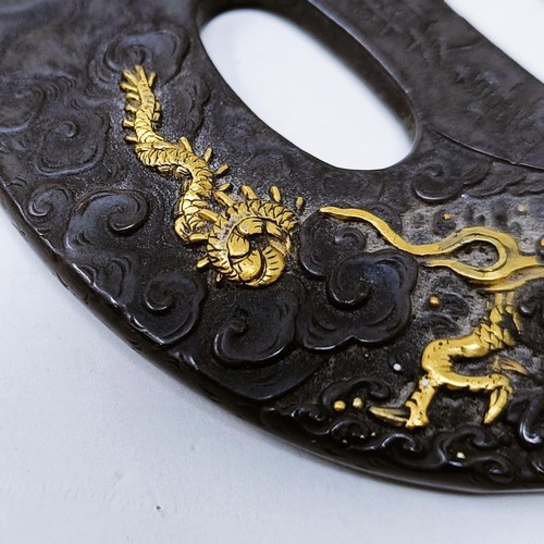 167 - A Japanese bronze tsuba, inlaid with gold, decorated a figure on horseback, and a dragon to one side... 