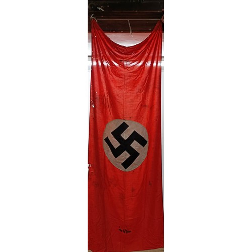 135 - A German Third Reich flag, with a swastika on a red ground, by family repute taken from town hall ba... 