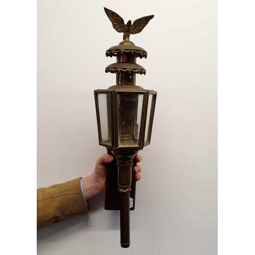 137 - An early 20th century brass oil carriage lamp, with an eagle finial, 59 cm high, mounted on a wooden... 