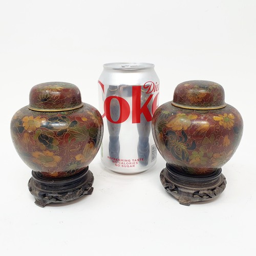 331 - A pair of modern cloisonné jars and covers, decorated flowers, 9 cm high, on carved wooden bases (2)