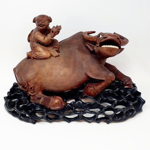 342 - A Chinese carving of a water buffalo, with a seated figure, on a hardwood stand, 40 cm high