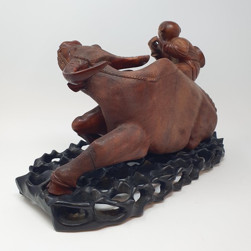 342 - A Chinese carving of a water buffalo, with a seated figure, on a hardwood stand, 40 cm high