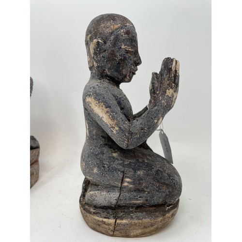 386 - An oriental figure of a praying man, 26 cm high, another similar, 27 cm high, and a carved stone fig... 