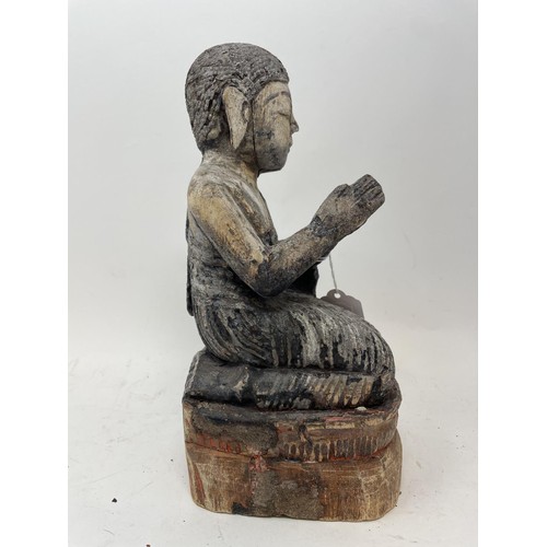 386 - An oriental figure of a praying man, 26 cm high, another similar, 27 cm high, and a carved stone fig... 