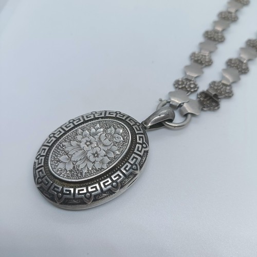 114 - A silver oval locket, on a fancy chain