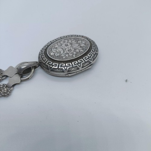 114 - A silver oval locket, on a fancy chain