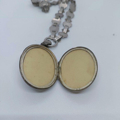 114 - A silver oval locket, on a fancy chain