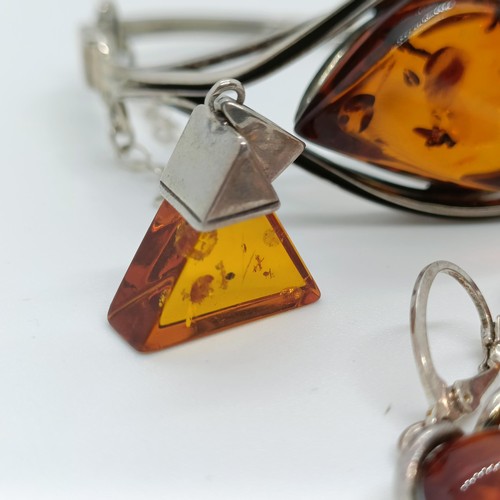 146 - An amber and silver coloured metal bangle, and four similar pendants