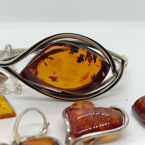 146 - An amber and silver coloured metal bangle, and four similar pendants