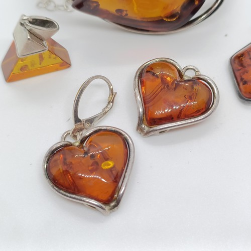 146 - An amber and silver coloured metal bangle, and four similar pendants