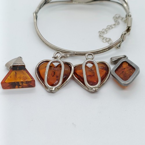 146 - An amber and silver coloured metal bangle, and four similar pendants