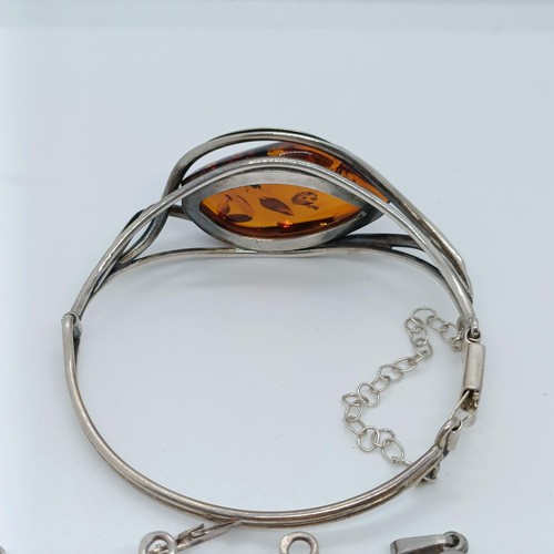 146 - An amber and silver coloured metal bangle, and four similar pendants