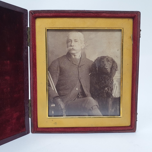 84 - A late 19th/early 20th century photograph of a gentleman with his pet dog, in a folding leather fram... 