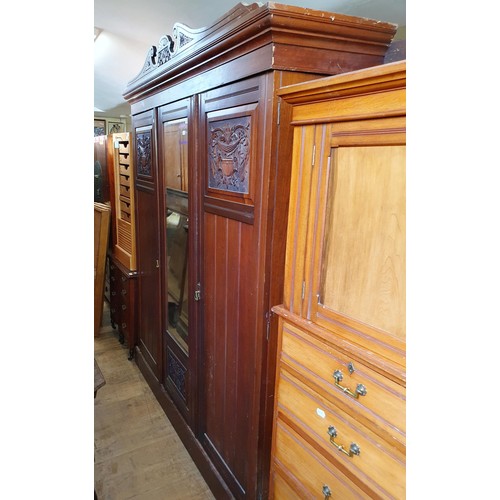 875 - An early 20th century walnut triple wardrobe, with a central mirrored door, 185 cm wide