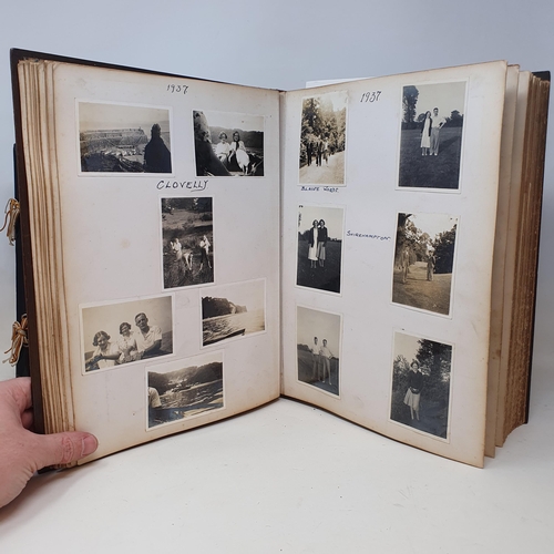 120 - An early 20th century photograph album, with a carved wooden cover, contents of family portraits and... 