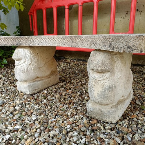 957 - A composite stone garden bench, with supports in the form of lions, 150 cm wide