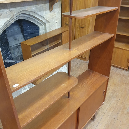 182 - A 1970s teak room divider, the top with open shelves on a base with two sliding doors on square tape... 