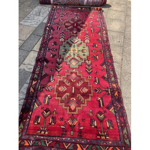 852 - A red ground Tribal rug, with green central medallion, 324 x 139 cm