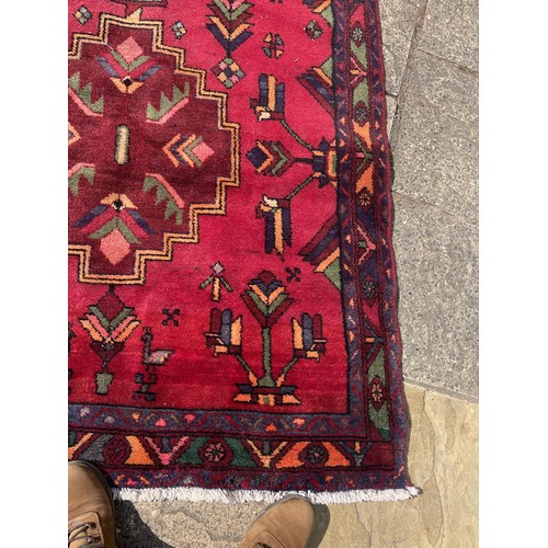 852 - A red ground Tribal rug, with green central medallion, 324 x 139 cm