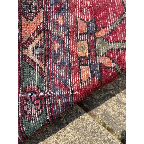 852 - A red ground Tribal rug, with green central medallion, 324 x 139 cm