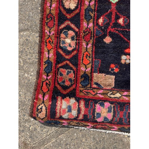 831 - A Persian red ground rug, stylised floral medallion, 270 x 150 cm