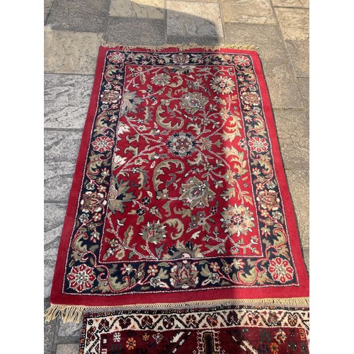 853 - A red ground Persian rug, 148 x 100 cm, and a red ground rug, 172 x 118 cm (2)