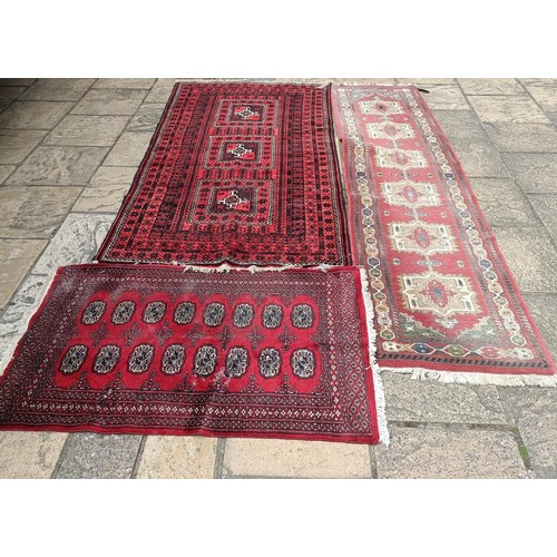 748 - A pink ground runner, 270 x 68 cm, a red ground rug, 137 x 80 cm, and another red ground rug, 214 x ... 