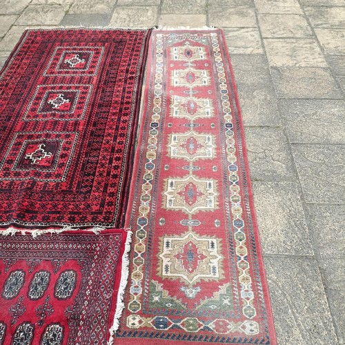 748 - A pink ground runner, 270 x 68 cm, a red ground rug, 137 x 80 cm, and another red ground rug, 214 x ... 