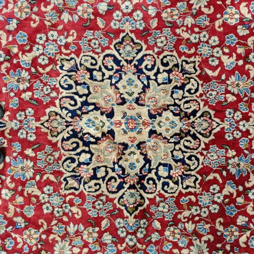 870 - A red ground Persian carpet, with a central blue cartouche, 370 x 257 cm