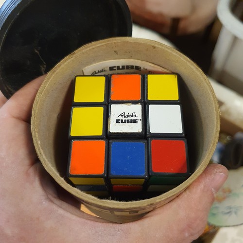 714 - A 1980s Rubix cube, boxed, a pair of child's leather shoes, and assorted other items (box)