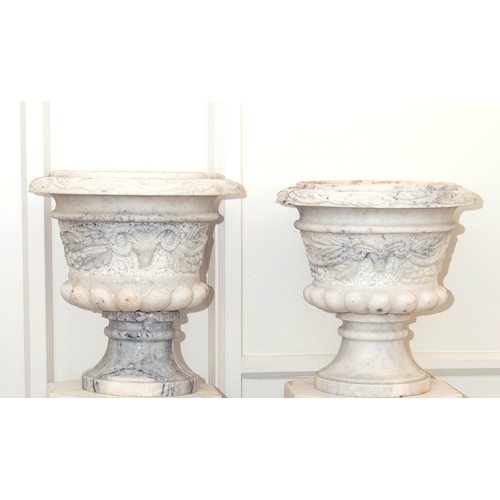 818 - A pair of carved white marble urns, decorated rams masks and foliage, 38 cm diameter