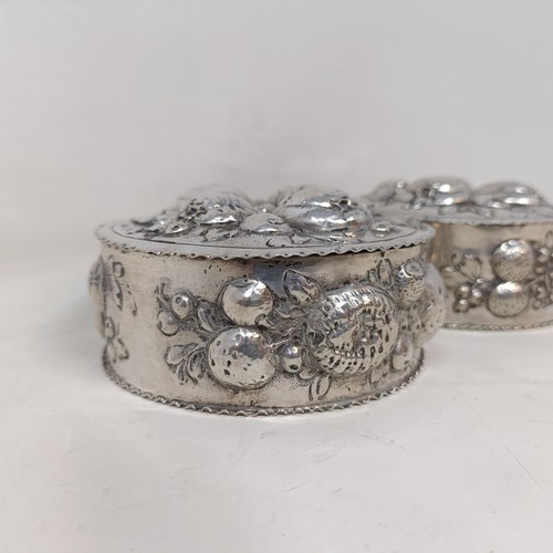 21 - A pair of Continental silver coloured metal boxes and covers, embossed fruit in high relief, 9 cm di... 