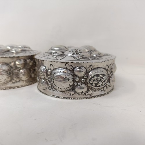 21 - A pair of Continental silver coloured metal boxes and covers, embossed fruit in high relief, 9 cm di... 