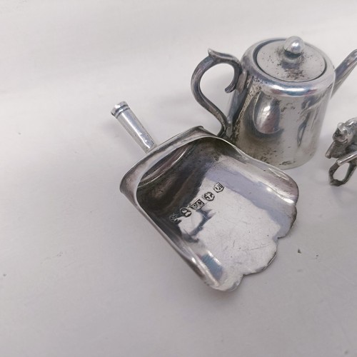 10 - A George V silver miniature teapot, a caddy spoon in the form of a shovel, and a silver coloured met... 