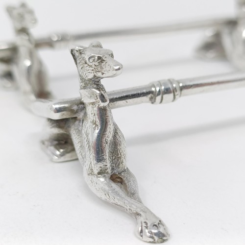 106 - A pair of Continental silver coloured metal novelty knife rests, in the form of dogs, with a crop re... 