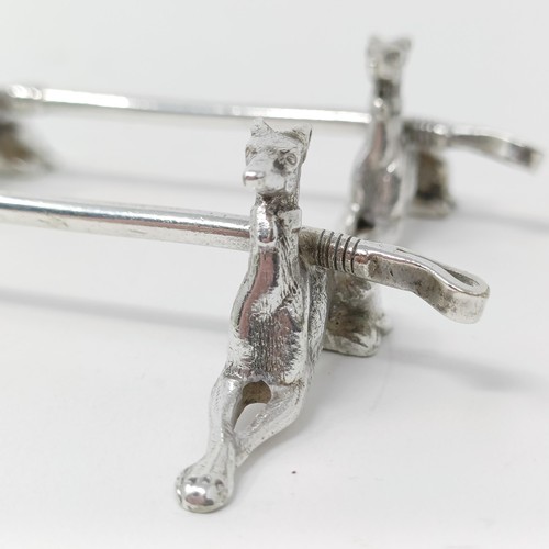 106 - A pair of Continental silver coloured metal novelty knife rests, in the form of dogs, with a crop re... 