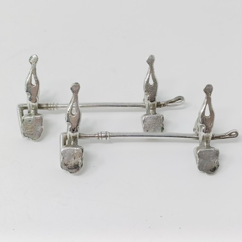 106 - A pair of Continental silver coloured metal novelty knife rests, in the form of dogs, with a crop re... 