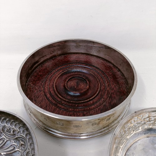 24 - An Elizabeth II silver and mahogany bottle coaster, a pierced silver bowl and bowl inset with a coin... 