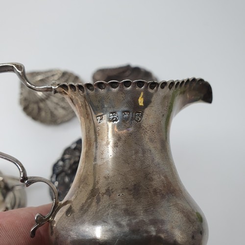 117B - A George II silver cream jug, a trophy cup, two shell form dishes, and a small swing handle basket, ... 