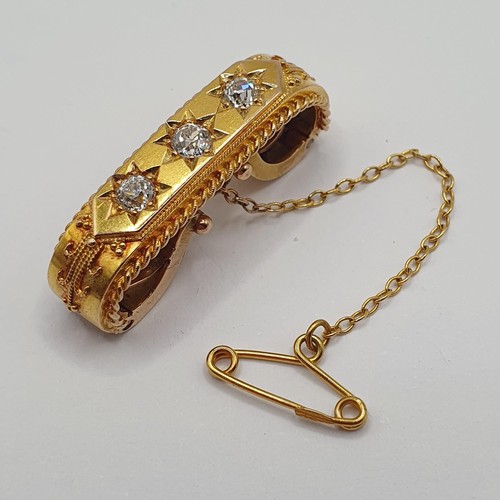 877 - A yellow coloured metal and three stone diamond brooch, with a clip back type setting, and a safety ... 