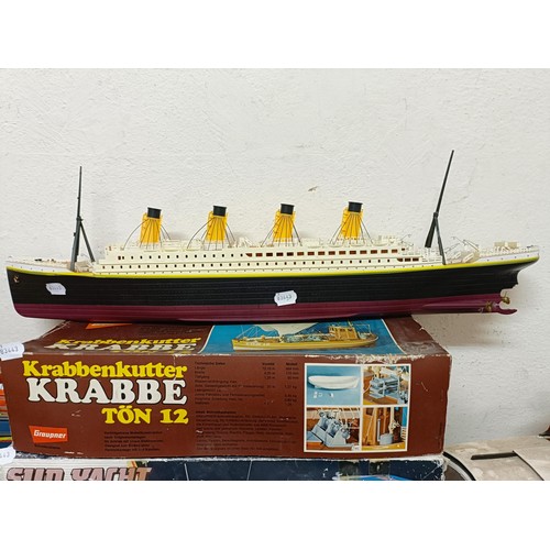 414 - A model boat, 29 cm wide, three model kits, boxed, and four other model boats (8)