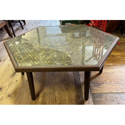 530 - An unusual low table, the hexagonal top set with brass 3d coins under a glass top