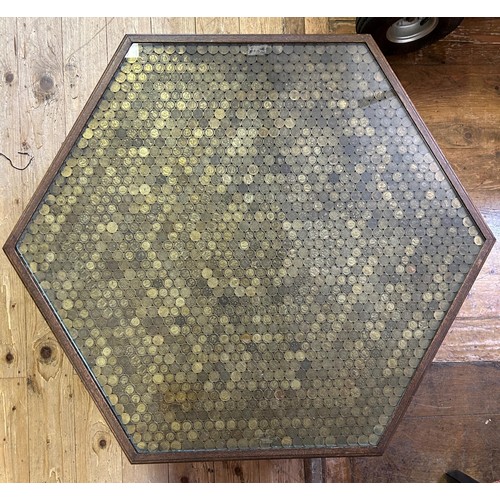 530 - An unusual low table, the hexagonal top set with brass 3d coins under a glass top