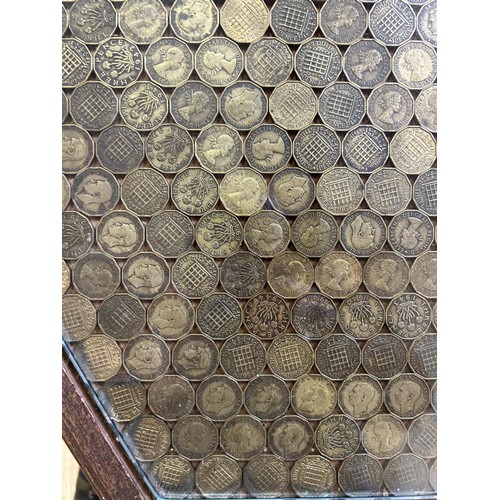 530 - An unusual low table, the hexagonal top set with brass 3d coins under a glass top