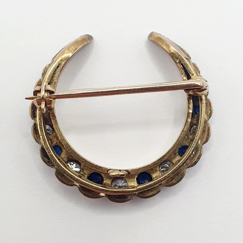 848 - An early 20th century yellow coloured metal, diamond and sapphire crescent shaped brooch, 3 cm wide