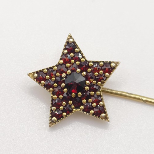 599 - A 20th century yellow coloured metal and garnet stick pin, in the form of a star Provenance:  From a... 